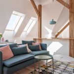 An updated attic with three skylights brightening the space with natural light, a small sitting area, and a kitchenette.