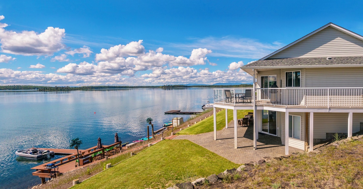 A lakeside home with an elevated deck overlooking a private dock, boat, and scenic waterfront views.