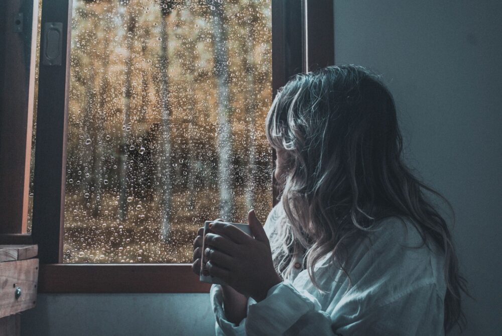 A woman enjoying a hot beverage on a rainy day